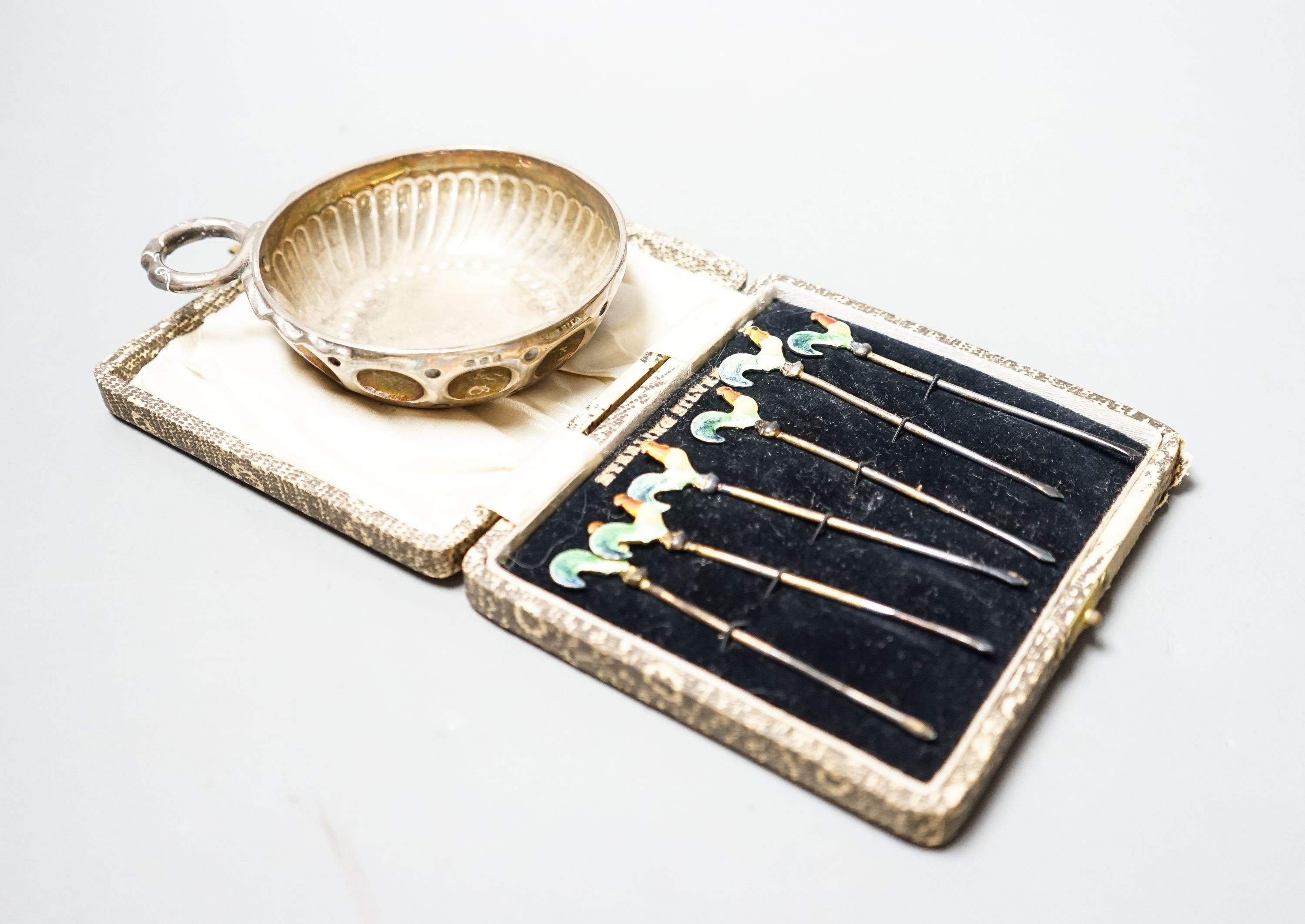 A 1930's silver taste vin and a cased set of six sterling and enamel cocktail sticks.